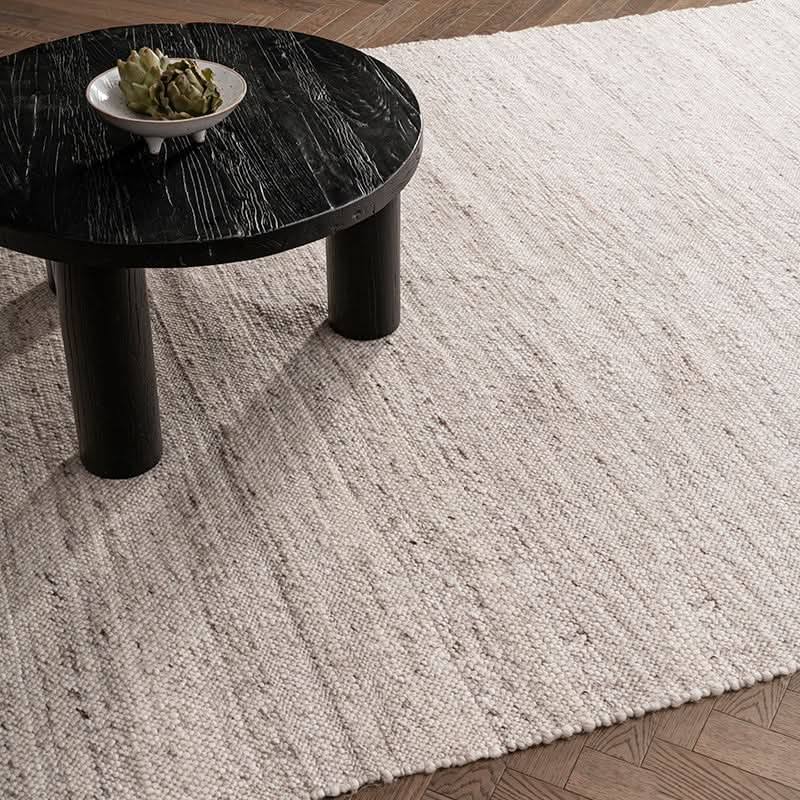 Natural Wool Carpet in a soft grey, textured weave, shown with a dark wood coffee table.