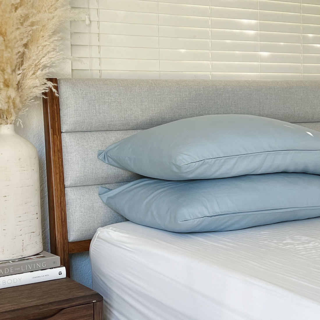 Light blue Copper Infused Bamboo Pillowcase Set on a bed with a grey headboard and white bedding.