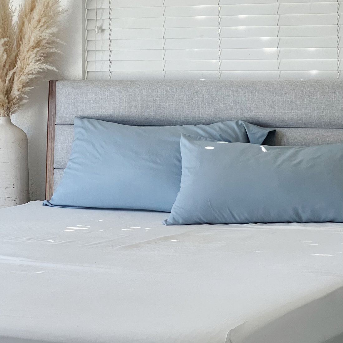 Sky blue Copper Infused Bamboo Pillowcase Set on a neatly made bed with a grey headboard.