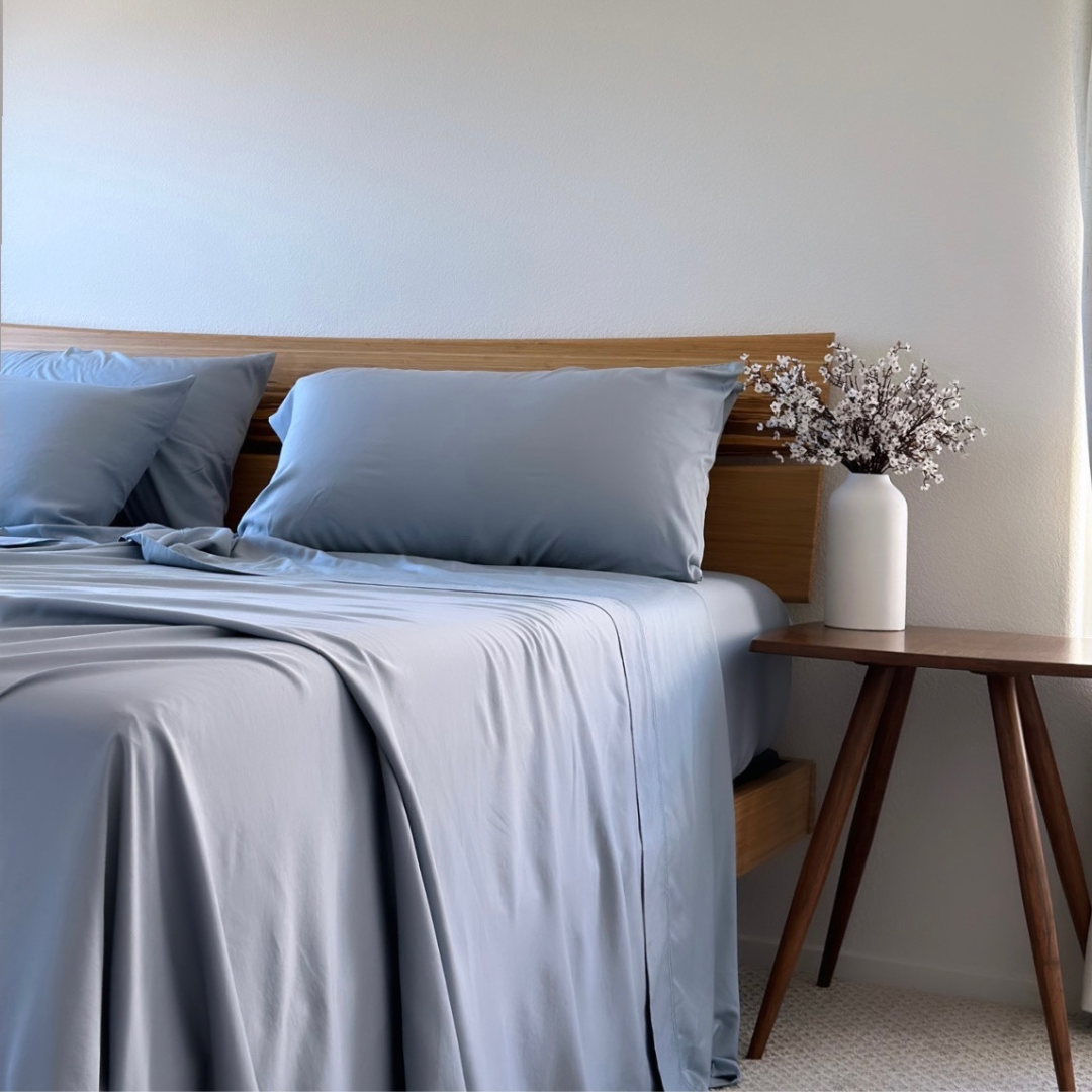 Grey Copper Infused Bamboo Pillowcase Set on a bed with a wooden headboard and side table.