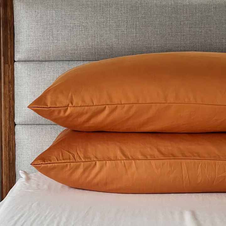 Two burnt orange Copper Infused Bamboo Pillowcases stacked on a white sheet.