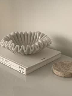 White fluted marble fruit bowl on stack of books, home decor accent.