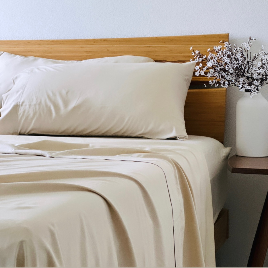 Soft beige Copper Infused Bamboo Pillowcase Set on a bed with a bamboo headboard.