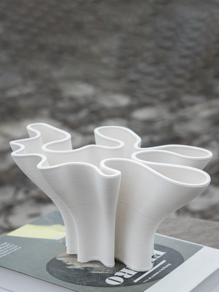 Modern abstract white ceramic vase, minimalist home decor on a book.