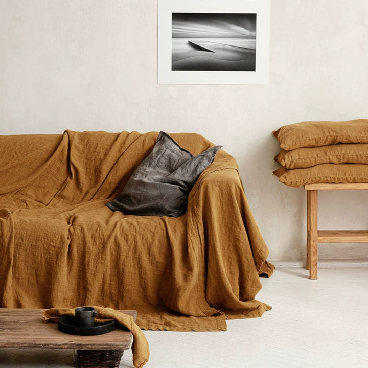 Mustard Yellow Linen Sofa Throw Blanket draped on sofa with grey pillow. Cozy decor.