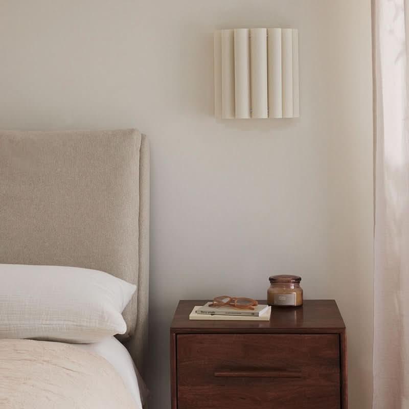 Modern Pleated Fabric Pendant Light in cream, mounted above a bedside table.