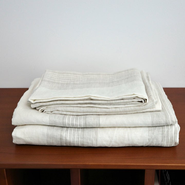 French Linen Striped Bedding Set in neutral tones, neatly folded on a wooden surface.