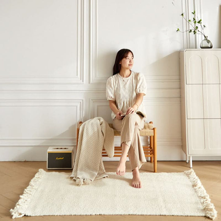 Cream braided wool rug with fringe, featuring a textured weave in a modern living space.