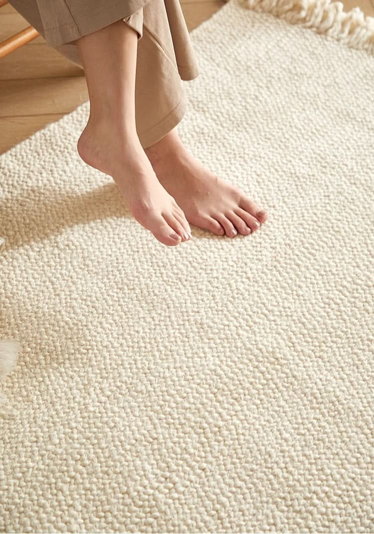 Cream braided wool rug with fringe detail, soft texture, home decor.