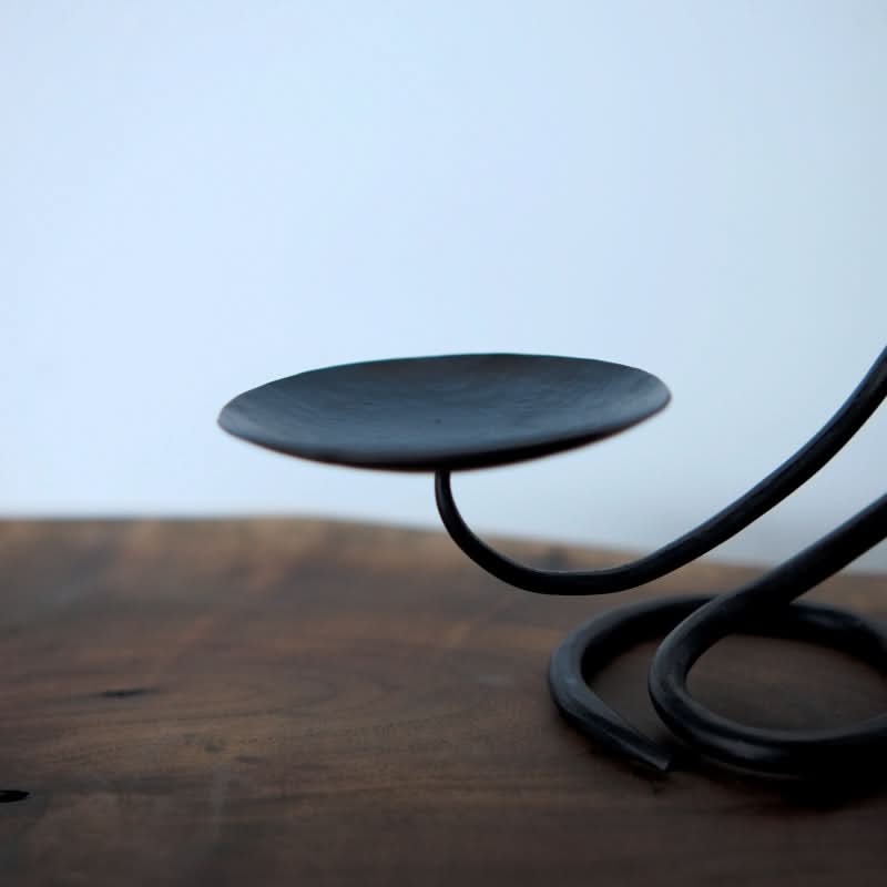 Stylish black candle holder made of metal, displayed on a wooden surface.