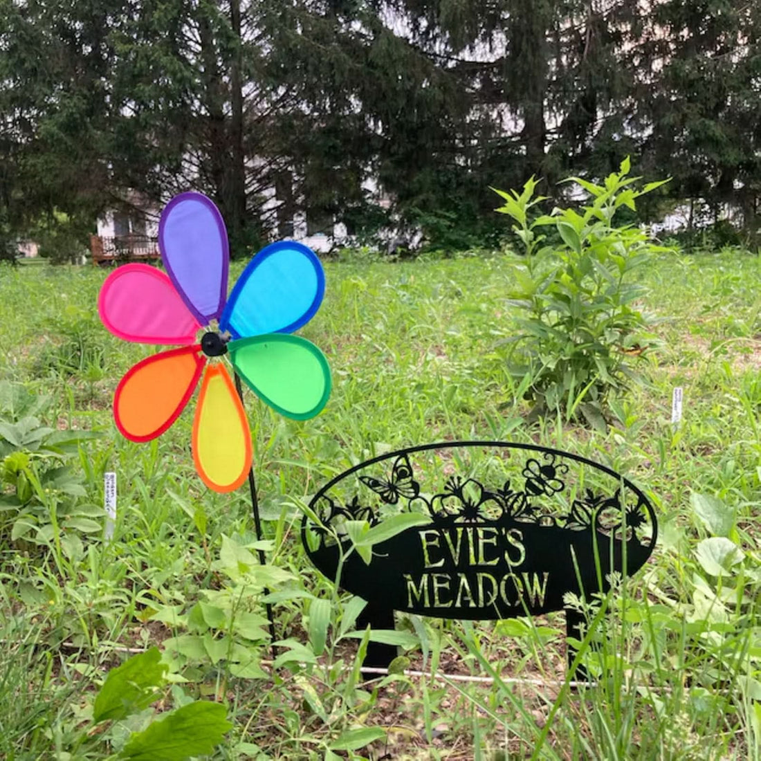Personalized Garden Metal Sign "EVIE'S MEADOW" with butterfly & bee design, green outdoors.