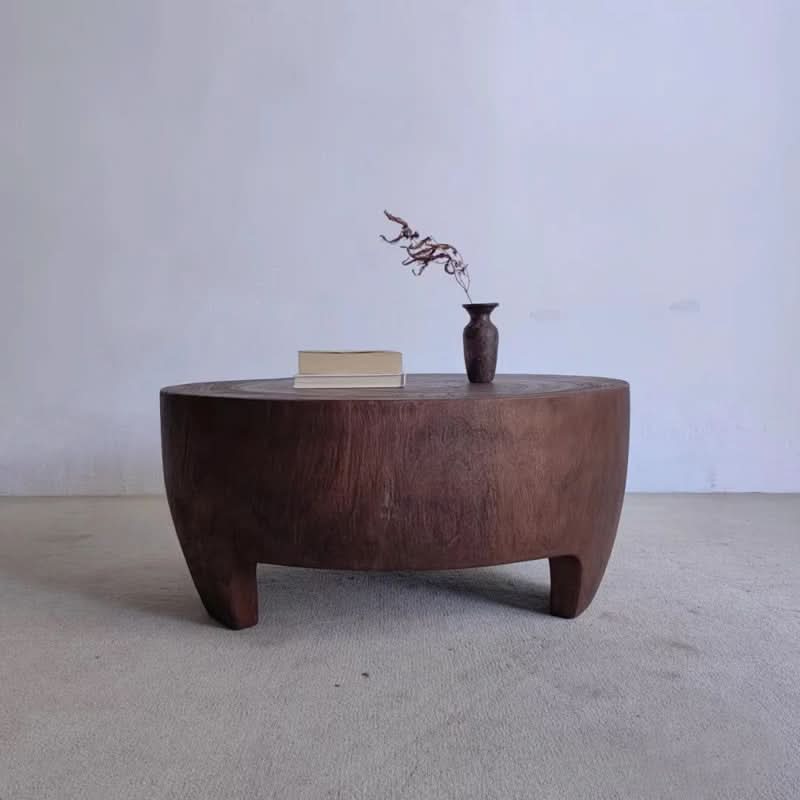 Rustic raw wood coffee table, dark brown, with vase and books.