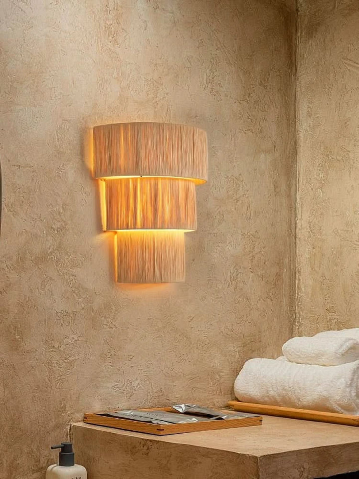 Natural Raffia Wall Sconce Light: layered, textured, warm illumination on textured beige wall.