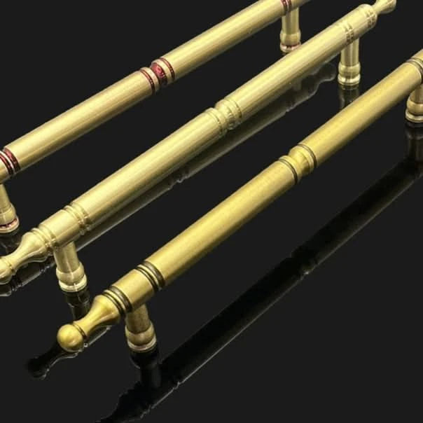 Solid brass cabinet handles in classic style, antique gold finish, on black background.