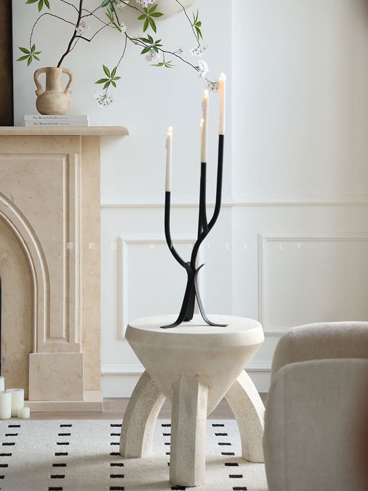 Modern Branch Candle Holder: Black minimalist candelabra with three lit candles on a stone pedestal table.