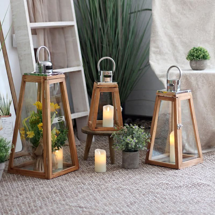 Triangular rustic wooden lantern with glass panels, candles, and greenery in a home decor setting.