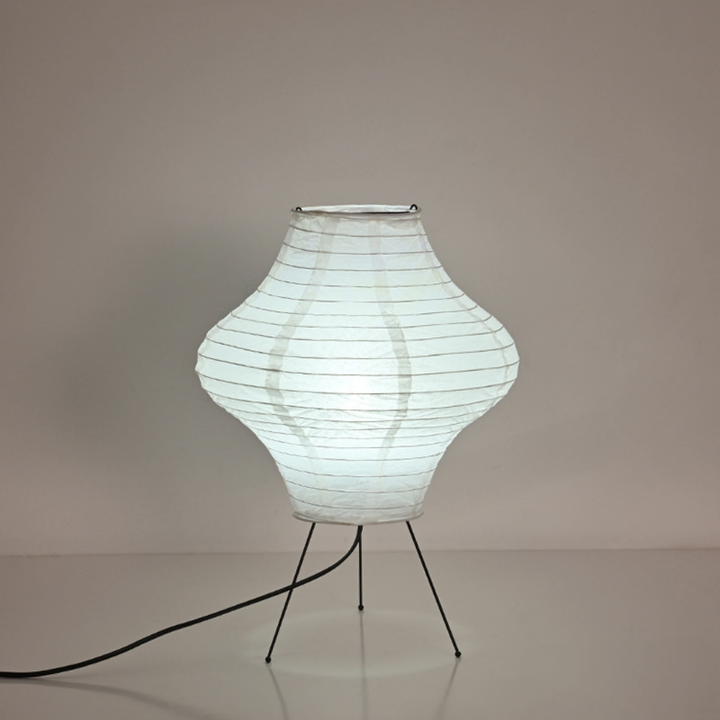 White paper desk lamp, diamond shape, on black tripod legs with cord.