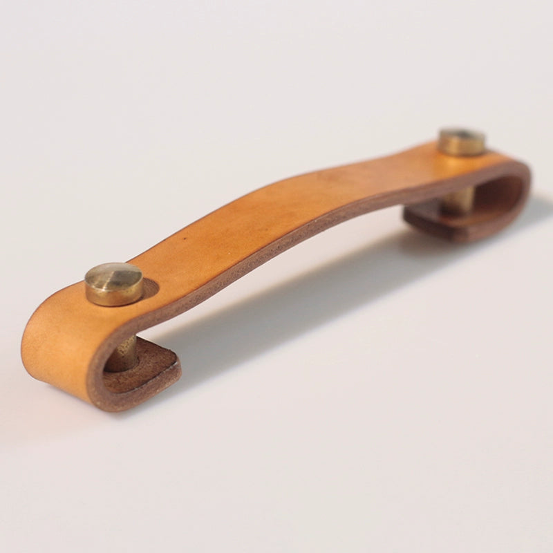 Rustic brown leather drawer pulls with brass hardware, perfect for wooden furniture.
