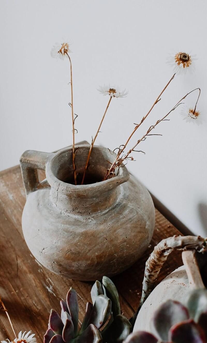 Antique style succulent clay pot, distressed earthenware with dried flowers on rustic wood.