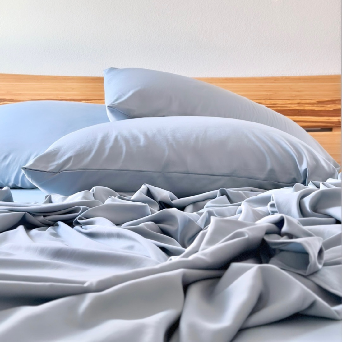 Soft grey Copper Infused Bamboo Pillowcase Set on a wooden headboard.