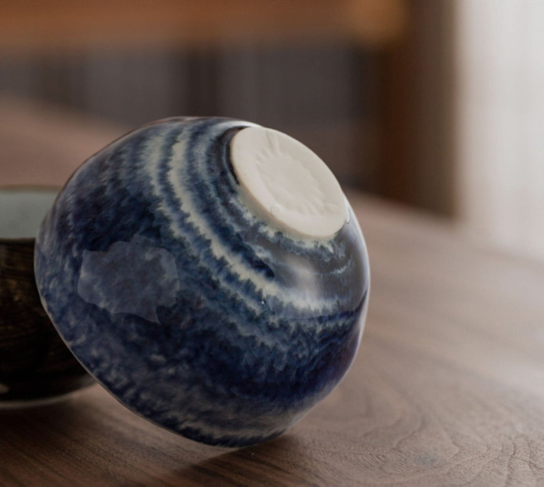 Blue and white ceramic Japanese tea set cup with textured glaze on wood table.