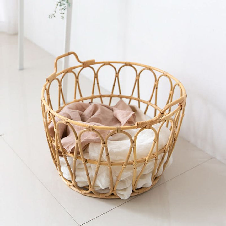 Natural rattan round storage basket with zig-zag pattern, holding soft linens.