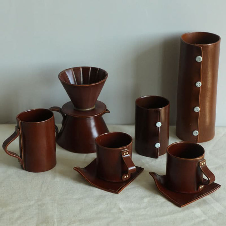 Brown ceramic cups textile folded style set with coffee brewer and mugs.