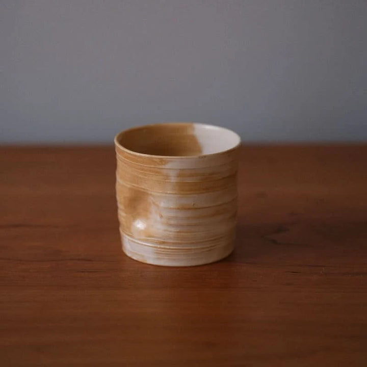 Handmade ceramic dented coffee cup in earthy tones, perfect for milk and home decor.