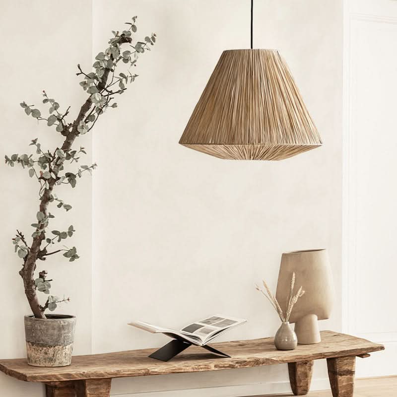 Natural raffia lampshade, triangle shape, hanging over a rustic wooden bench with home decor accents.