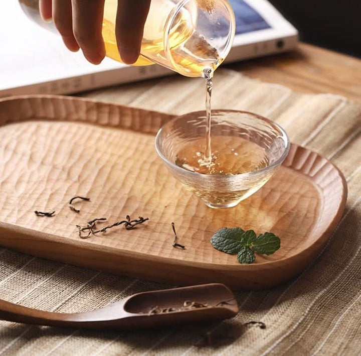 Carved wooden coffee tray with tea pouring, featuring rustic farmhouse charm.