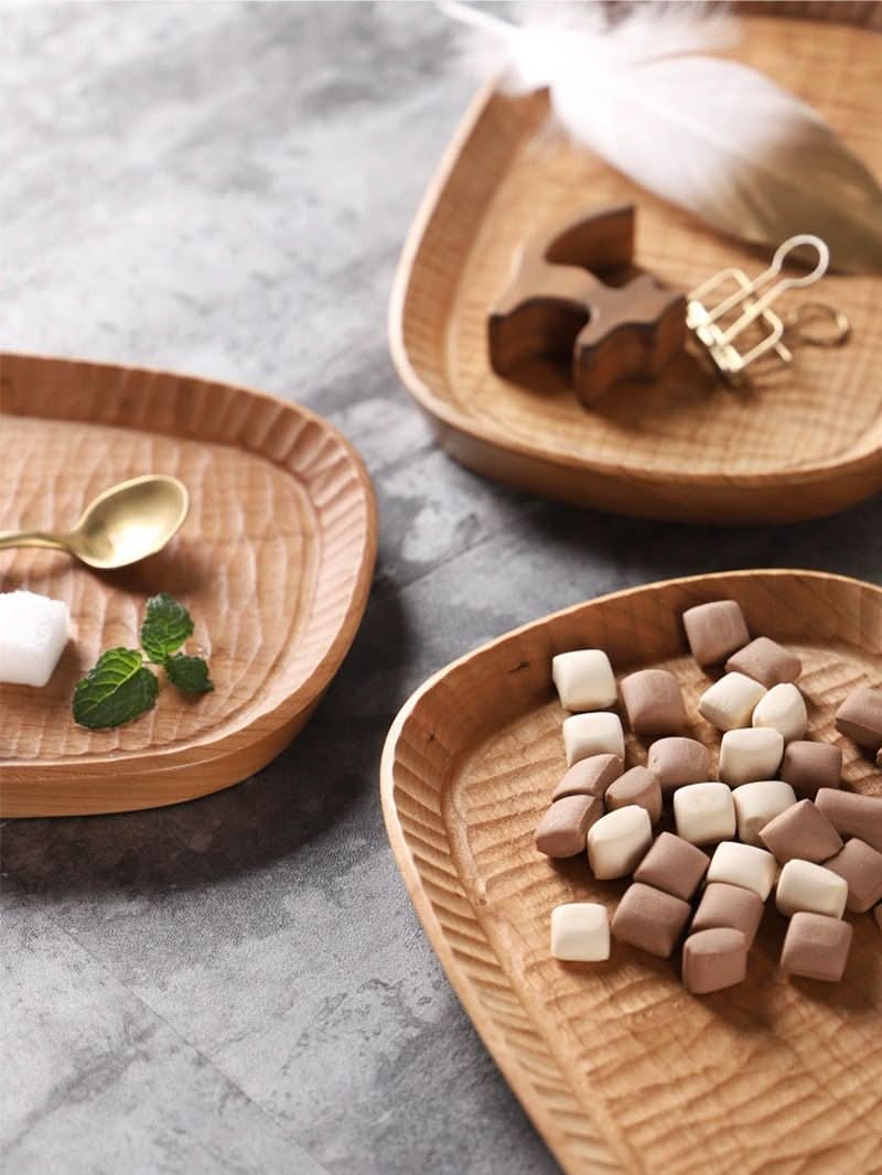 Carved wooden coffee tray with mint, sugar, and marshmallows on rustic surface.