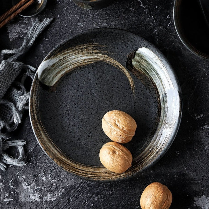 Japanese rustic ceramic bowl with spoon, glazed, dark grey with brushstroke accents.