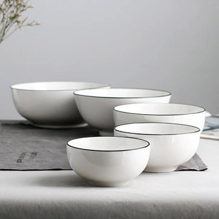 Set of 4 Japanese ceramic white bowls with black edges on a neutral surface.