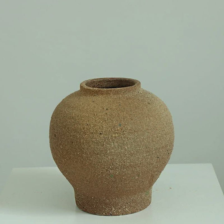 Brown Danish-style rough earthenware vase on white surface.