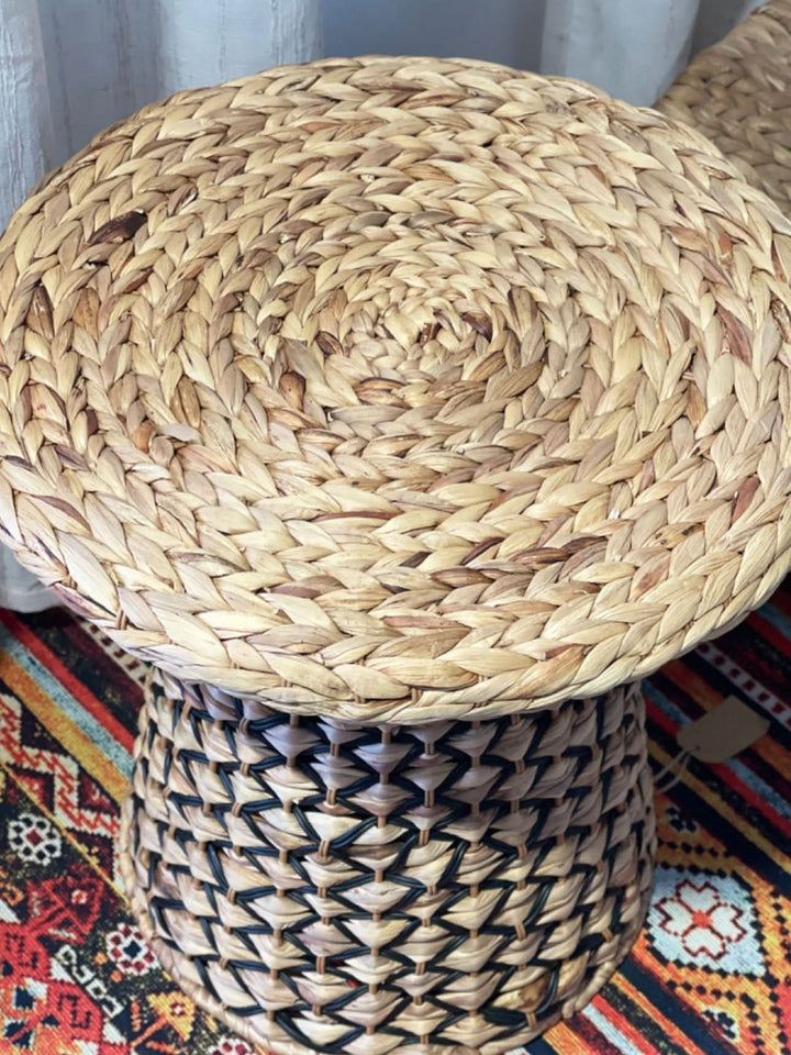 Wabi Sabi Coffee Table in natural straw weave with black accents, on a colorful rug.