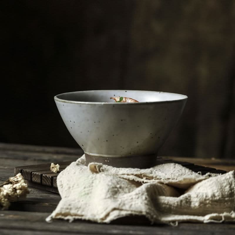 Handmade rustic clay bowl, 6.5", light grey speckled stoneware, holding food on a wooden table.