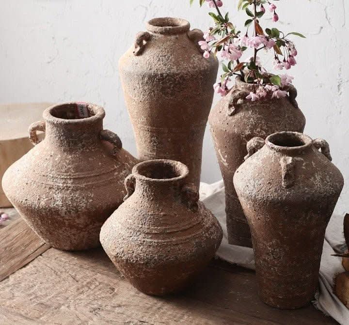 Rustic handmade pottery vases in earth tones, for succulents or dried flowers, on a wooden surface.