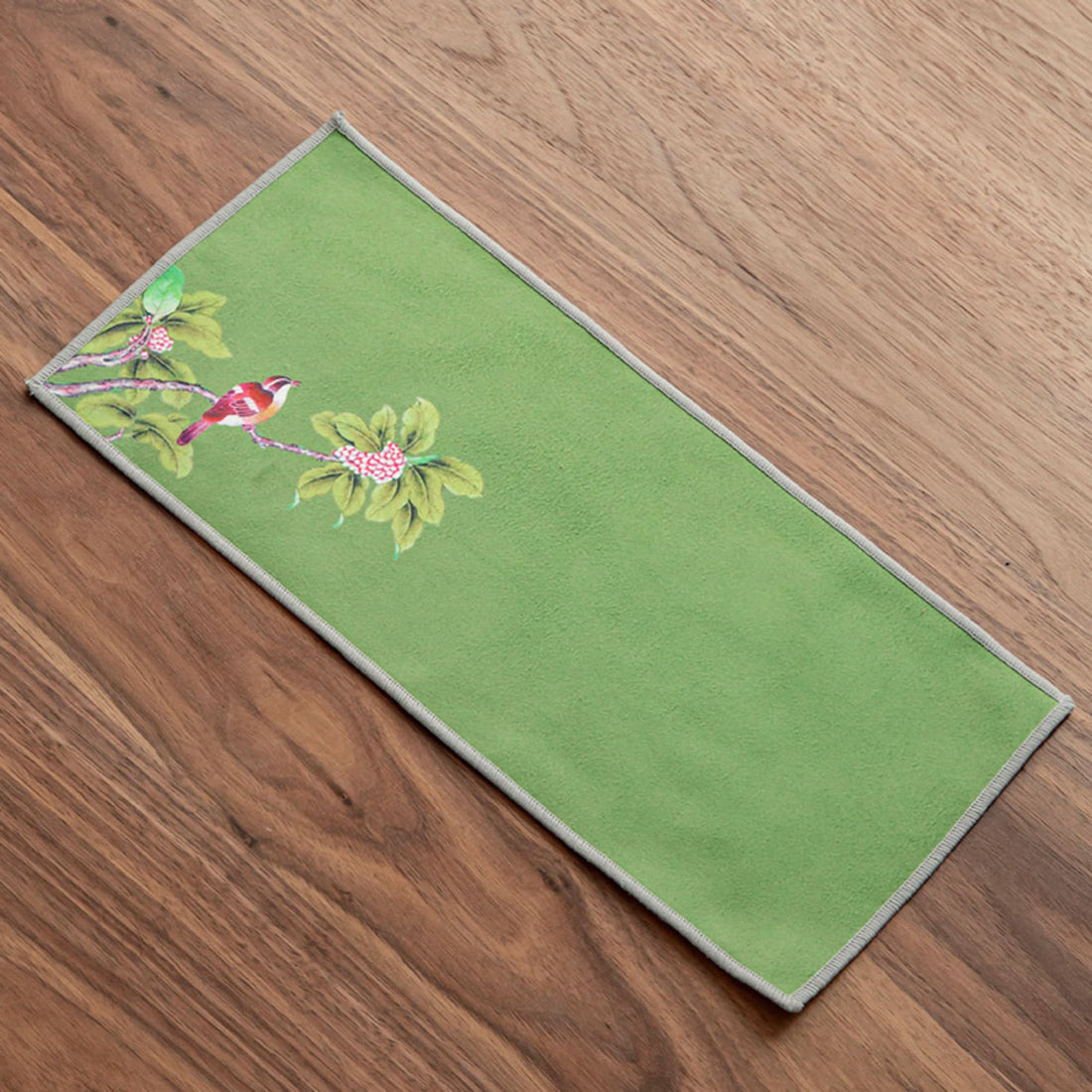 Ukiyo-e Japanese tea towel with bird and floral design on green fabric, on wooden surface.