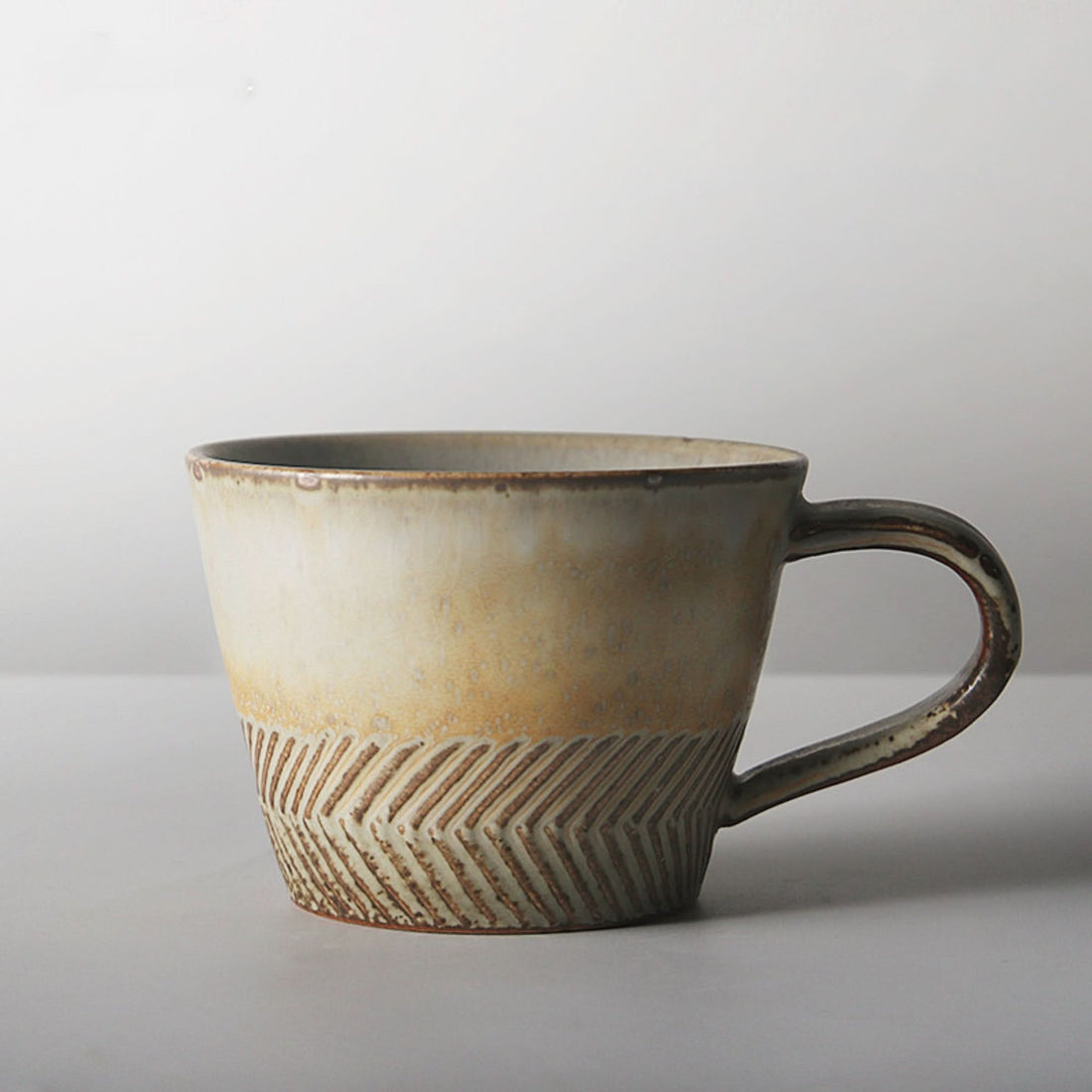 Japanese stoneware mug with carved detail, cream and brown glaze.
