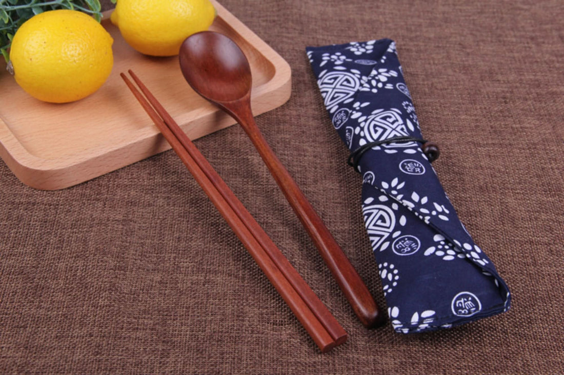 Natural wooden Japanese cooking utensils with spoon and chopsticks in a blue patterned fabric case.