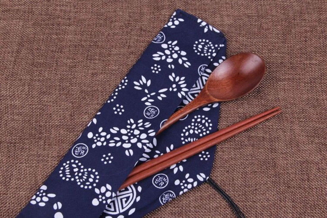 Japanese wood cooking utensils with natural spoon set & fabric case on brown textured background.