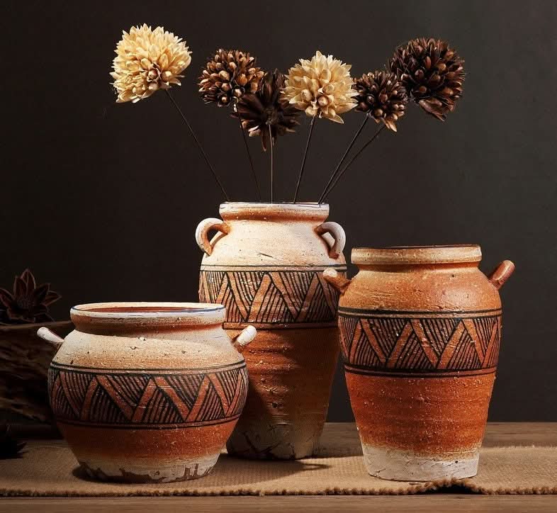 Antique ethnic vase with black tribal V patterns, terracotta with handles and dried flowers.