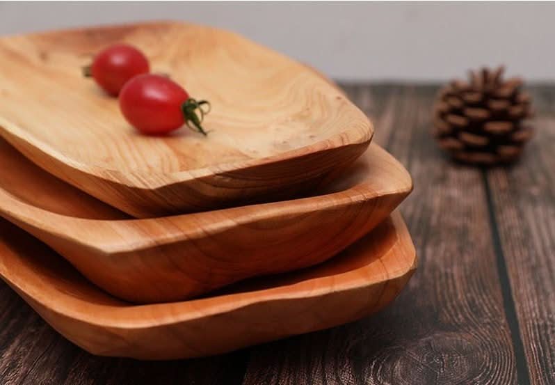 Irregular Wooden Plate: Stacked natural wood dishes with cherry tomatoes on top. Rustic farmhouse decor.