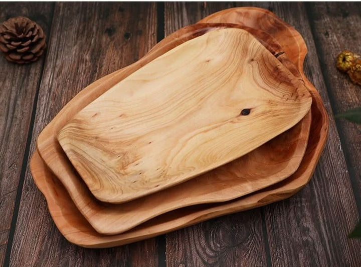 Rustic irregular wooden plates stacked on a dark wood surface. Perfect for farmhouse decor.