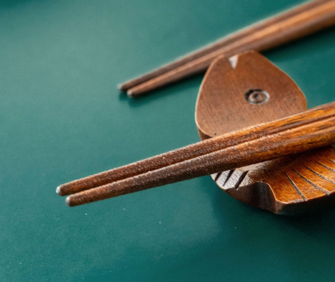 Japan imported handmade wooden chopsticks on a green surface, cute fish design.