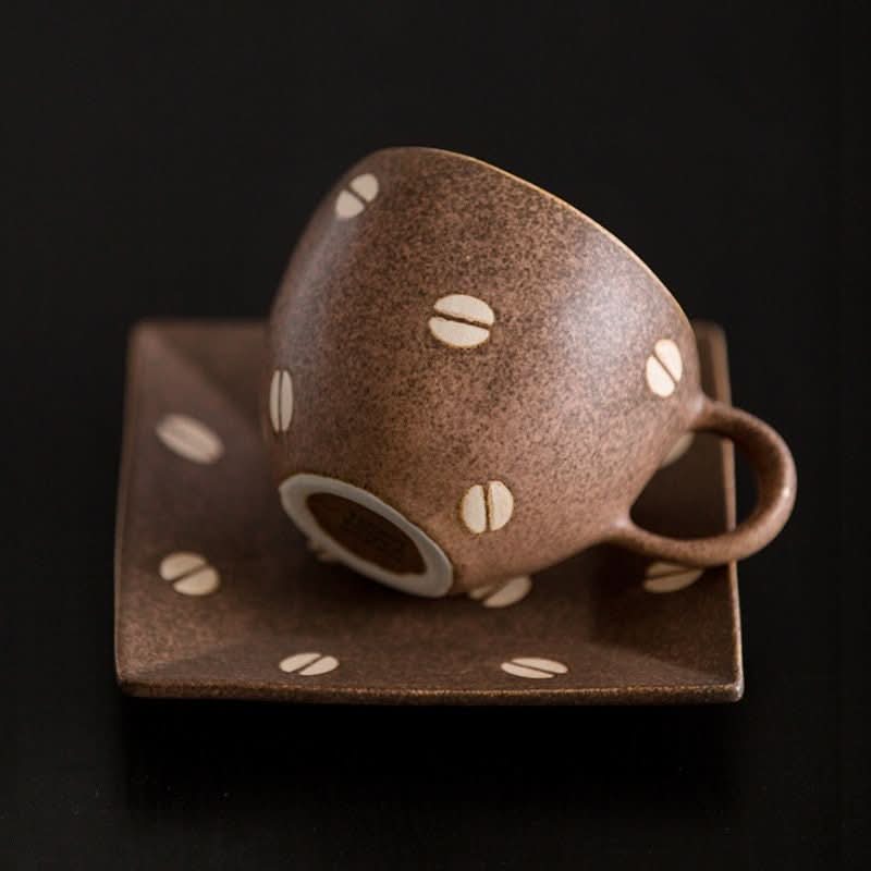 Brown speckled ceramic coffee cup with white bean design, on matching saucer. Japan Imported Mino Burn Ceramic.