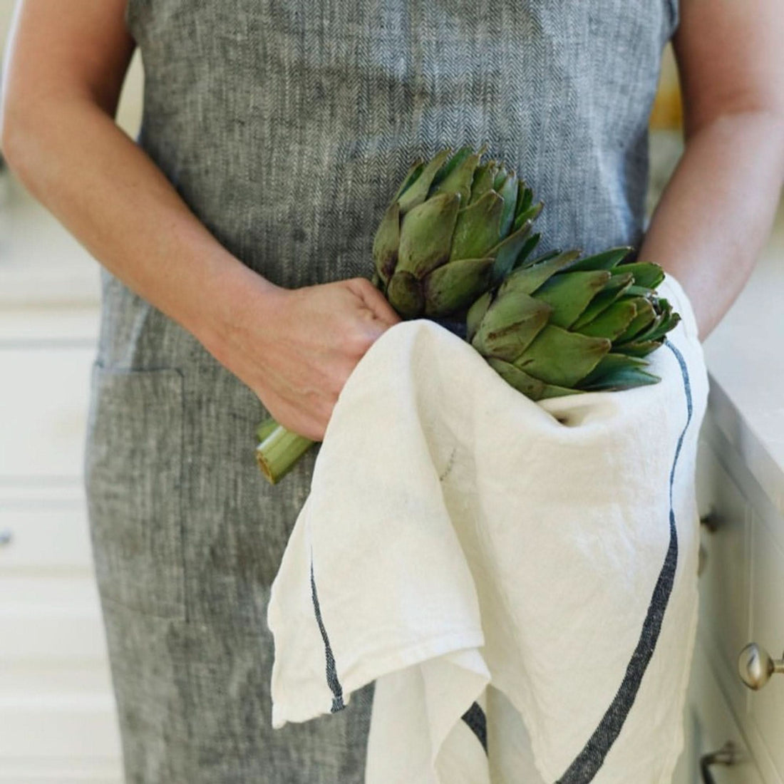 Japanese linen tea towels: off-white with navy stripes, holding fresh artichokes.