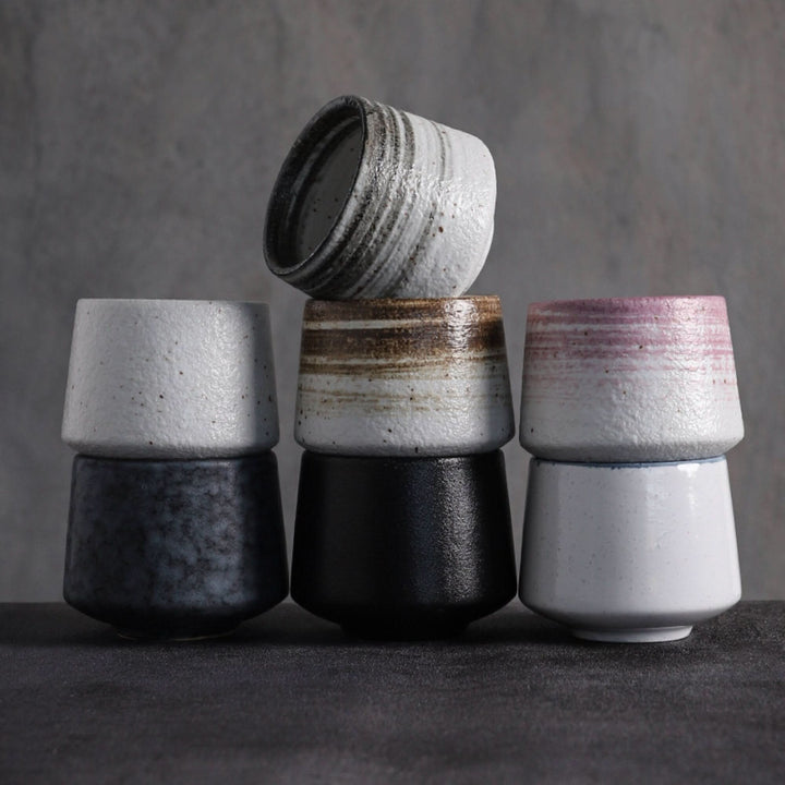 Stack of Japanese tea cups in gray tones with textured ceramic finish and varied glaze accents.