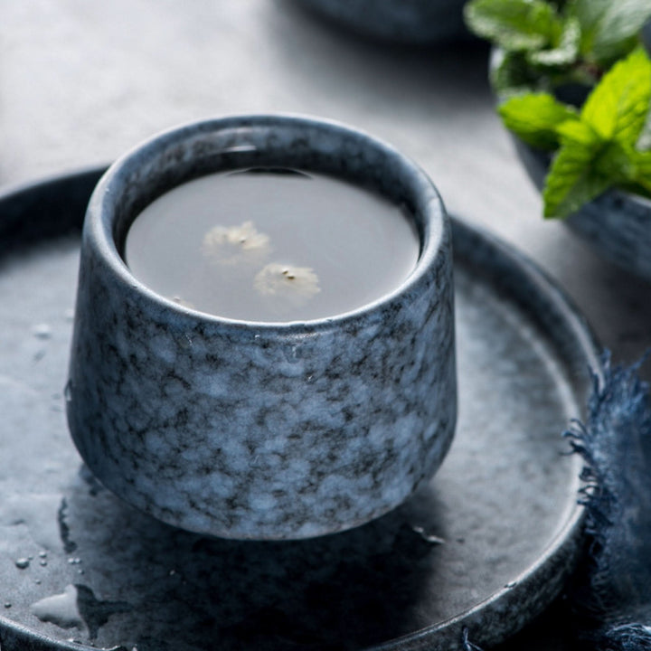Gray toned Japanese tea cup with ceramic texture, filled with tea.
