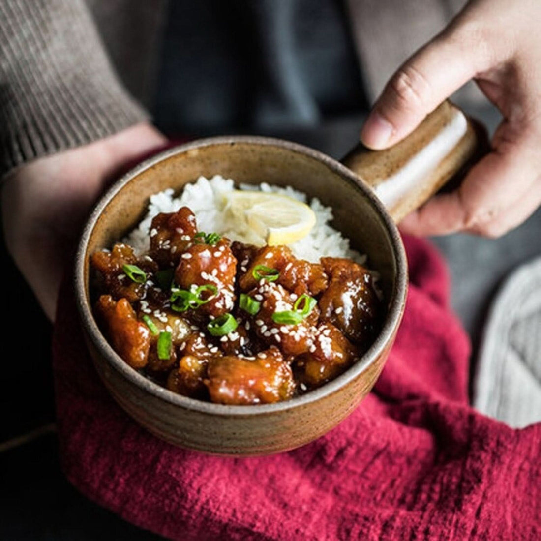 Rustic Nordic stoneware baking plate holds glazed chicken and rice, garnished with sesame seeds.